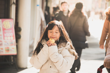 Obraz premium Beautiful Asian girl eating muffin in the city street,