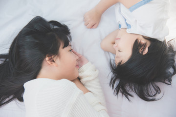 Obraz na płótnie Canvas Cute asian children lying on white bed