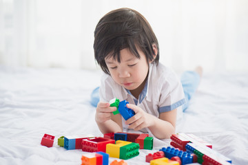 asian child playing with colorful construction blocks