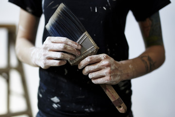 Painter holding paint brush with paint covered hands