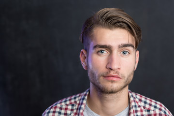 Handsome young student in shirt standing against blackboard