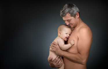 father holding a baby on a dark background