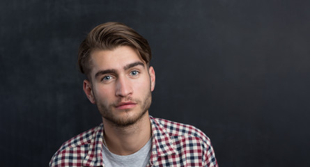 Obraz premium Handsome young student in shirt standing against blackboard