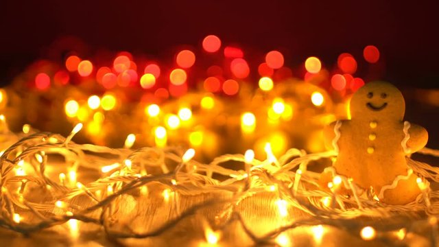 Ginger Disco - Gingerbread man cookie tangled up in golden Christmas lights, defocused background and ending of the clip, cheerful disco New Year background video