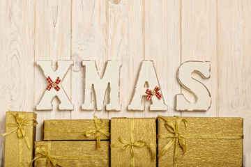 Wooden white XMAS letters on a white wooden background with gift