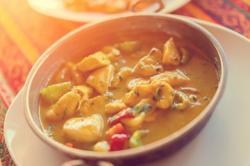 Vegetable stew or soup in a bowl on a white plate, sunny