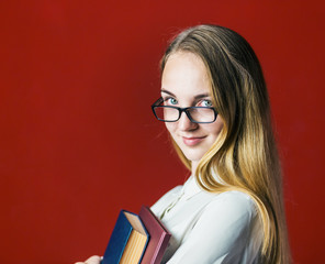 attractive happy smiling student blonde girl in white shirt with books on red background, student concept