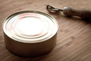 tin can and can opener on wooden background