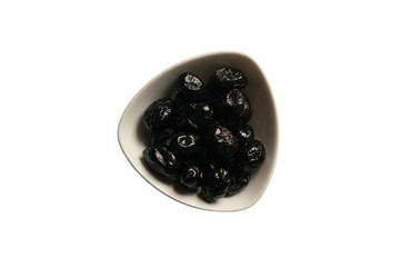 Small plate with black sun-dried olives in white plate on a white background. Isolated