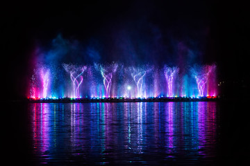 Beautiful fountain dancing show with reflection on water at night.