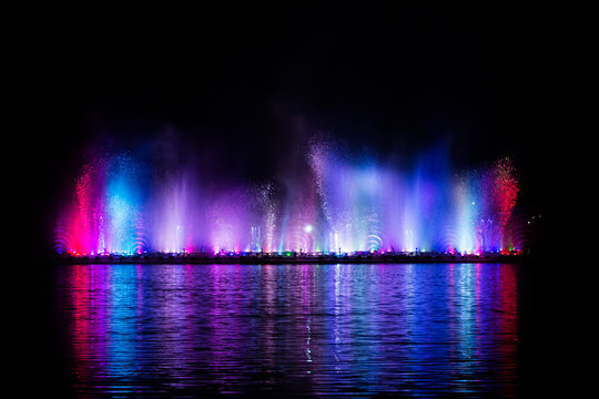 Beautiful fountain dancing show with reflection on water at night.