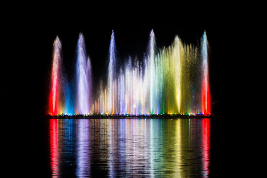 Beautiful fountain dancing show with reflection on water at night.