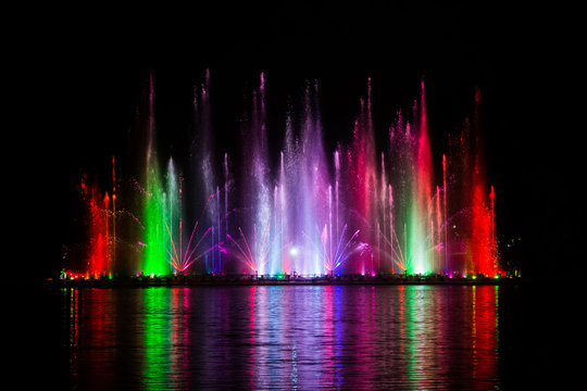 Beautiful fountain dancing show with reflection on water at night.