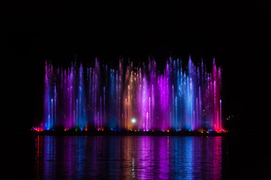 Beautiful fountain dancing show with reflection on water at night.