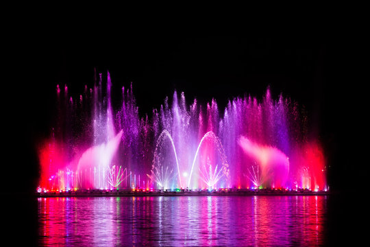 Beautiful fountain dancing show with reflection on water at night.