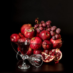 Still life on a dark background. Wine (liquor) glasses, fruits a
