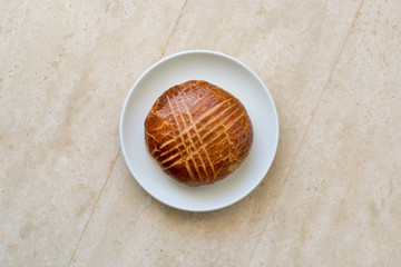 Ruddy muffin in a white plate on a wooden table