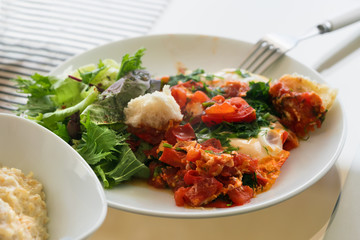 Omelette with tomatoes and greens on a white plate