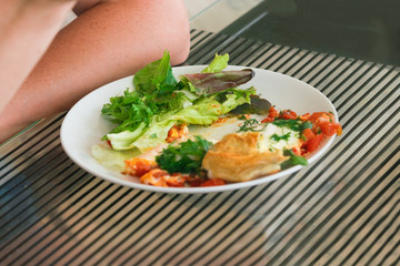 White plate with remnants of food on the glass table and human hands