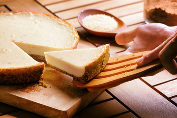 Hands taking piece of freshly baked cheesecake. Sweet dessert
