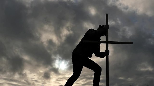 Silhouette of Man fixes the cross - dramatic concept - partially slow motion