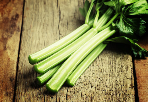 Stems of fresh celery with leaves on the table, vintage wooden b