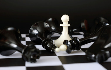 Pawn among fallen enemies. Winner and total victory. Concept with chess pieces against black...