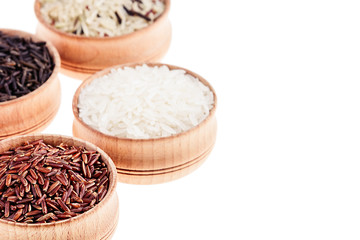 Red, black and white rice close-up in wood bowls on white background. Isolated. Rice texture background.