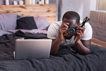 Young man holding a camera in his bedroom