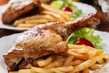 Roasted chicken legs with french fries and lettuce