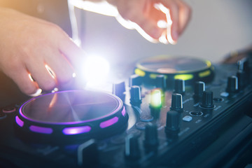 DJ turntable console mixer controlling with two hand in concert nightclub stage.