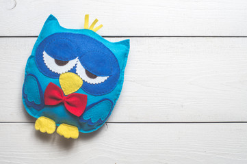 Owls of colored felt on white wooden boards