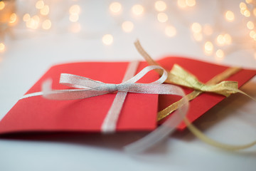 close up of two red greeting cards with ribbon bows on white background with christmas lights