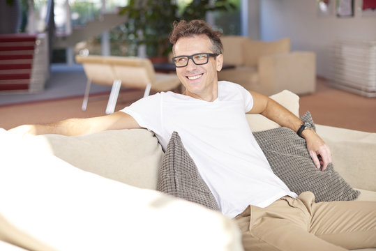 Relaxed man at home. Shot of a smiling middle aged man relaxing on sofa at home.