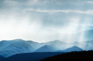Mountains and Hills with many stacked foggy, rainy and smoky ranges highlighted with backlight and sunlight, bird eagle, flying around, view from above