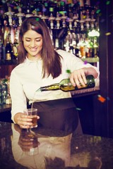 Composite image of pretty bartender pouring whiskey in glass