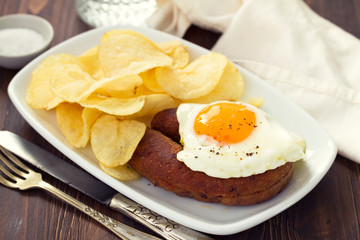 fried portuguese sausage alheira with egg and potato chips on white dish