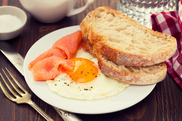 fried egg with smoked salmon and bread on white plate