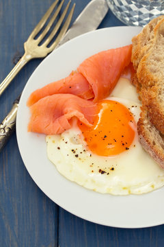 fried egg with smoked salmon and bread on white dish