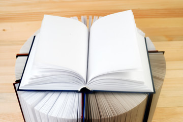 Open book, stack of hardback books on wooden table. Back to school. Copy space