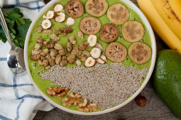 Detox healthy green smoothie bowl with bananas and feijoa, chia, mulberry, nuts, avocado
