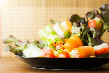Close up of fresh salad of lettuce, cucumber and tomato on plate for healthy eating..Fresh vegetable salad in Black plate  on wood table. Salad for healthy. Fresh raw vegetables salad background.