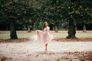 Fototapeta na wymiar beautiful woman in long rose evening dress walking path in park.