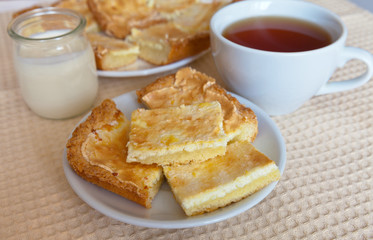 Homemade cottage cheese biscuits, a jar of yogurt and a cup of tea on the table. Fresh breakfast