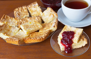 Homemade cookies with a layer of cottage cheese and a cup of tea on the table