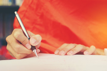 Monk's Hand writing in a book with the pencil