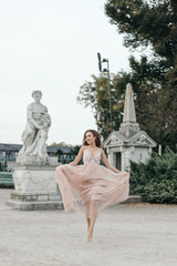 Young beautiful woman in long rose evening dress walking path in