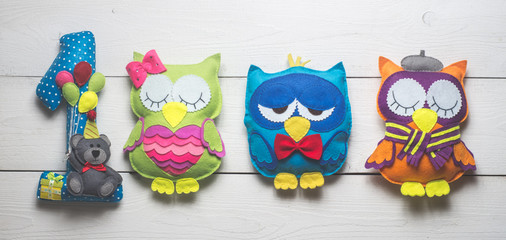 Owls of colored felt on white wooden boards