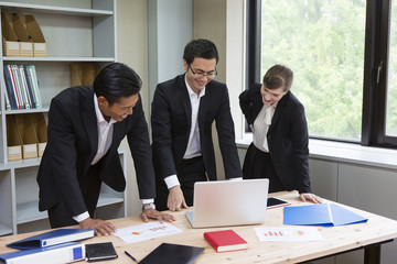 机を囲んで話すビジネスパーソン