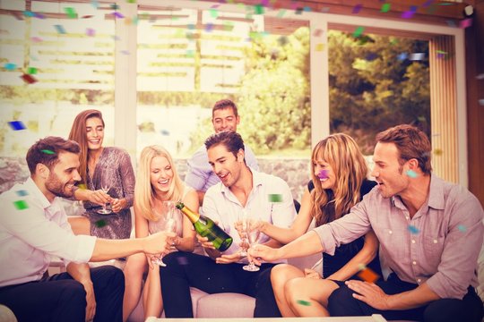 Composite image of man pouring champagne for friends